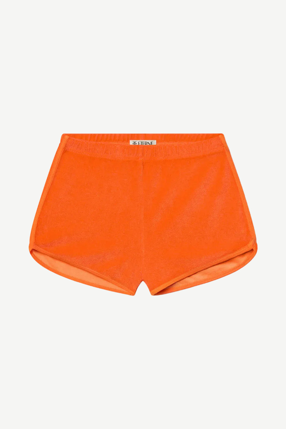The Mini Track Short, featured in a vibrant orange terry cloth, showcases an elastic waistband, a subtle front label, and curved side hems. Displayed against a plain white background, this slim fit design combines comfort and style for athletic wear.