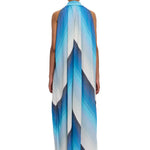 A person stands facing away, wearing The Halter Dress Small Point Collar—a long, flowing halter dress featuring blue and white diagonal stripes and crafted from handwoven cotton. Their hair is tied back in a neat bun, set against a plain white background.