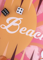 The Miami Backgammon Board Game features a pink acrylic board with vibrant orange accents and the word “Beach” written in white script, surrounded by dice and game pieces. This stylish set comes packaged in a chic gift box, making it the perfect choice for any game enthusiast.