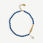 KABE SHOP INC Ospina necklace featuring blue lapis beads, a gold fish pendant, and a freshwater pearl charm.