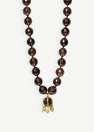 KABE SHOP INC Lark Drip necklace with faceted smoky quartz beads, gold claw pendant, and small peridot drop accents.