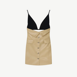 The Zyana Dress is a sleeveless style with a fabric-blocked design, showcasing a black deep V-neck top paired with a beige faux leather skirt featuring a button-down front and flap pockets. The dress is displayed against a plain background.