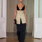 A model walks indoors wearing the Zyana Dress. The background features cream curtains and white paneled walls.