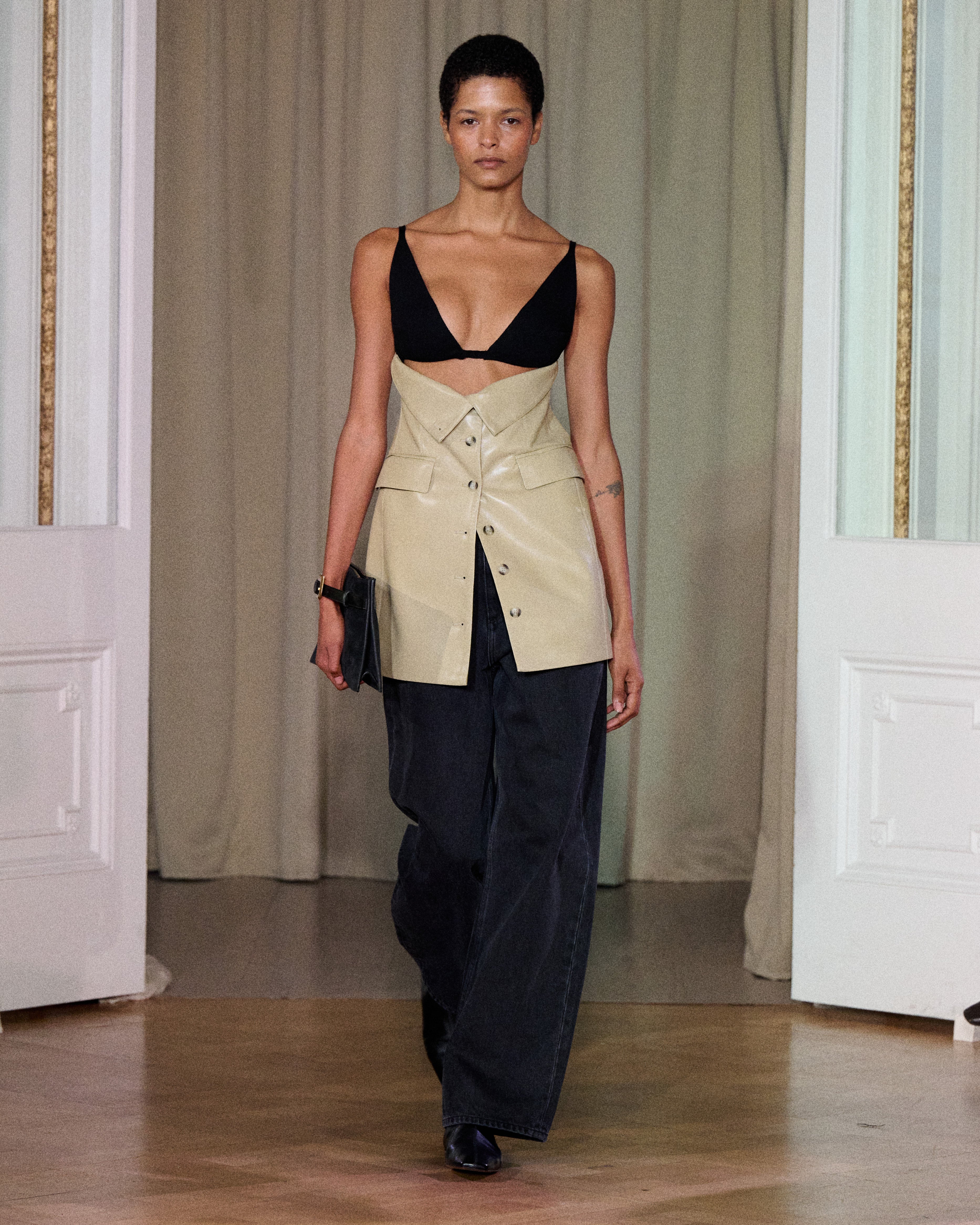 A model walks indoors wearing the Zyana Dress. The background features cream curtains and white paneled walls.