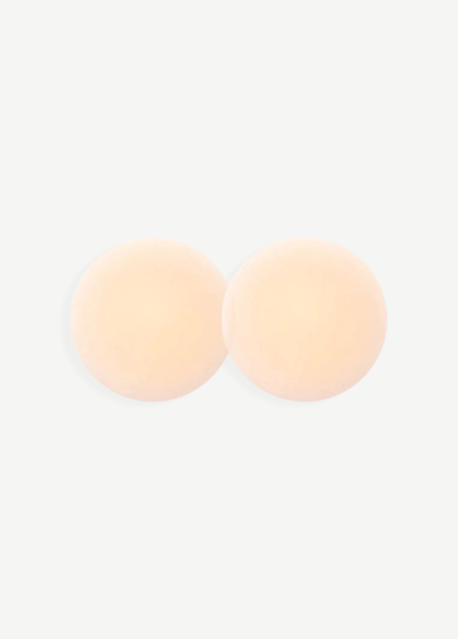 Two round, skin-toned Reusable Nippz self-adhesive nipple covers rest on a plain white background, slightly overlapping in the center. These washable covers offer a seamless and comfortable fit for everyday wear.