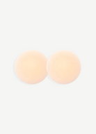 Two round, skin-toned Reusable Nippz self-adhesive nipple covers rest on a plain white background, slightly overlapping in the center. These washable covers offer a seamless and comfortable fit for everyday wear.