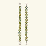 Two vertical strands of round, green marbled beads with wire hooks at each end serve as elegant jewelry straps for the Dolores Top Classic Swimwear, set against a plain light background.
