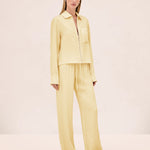 A model wears a pale yellow zip-up shirt and matching Damian Pant wide-leg trousers with an elastic drawstring waist for a polished style.