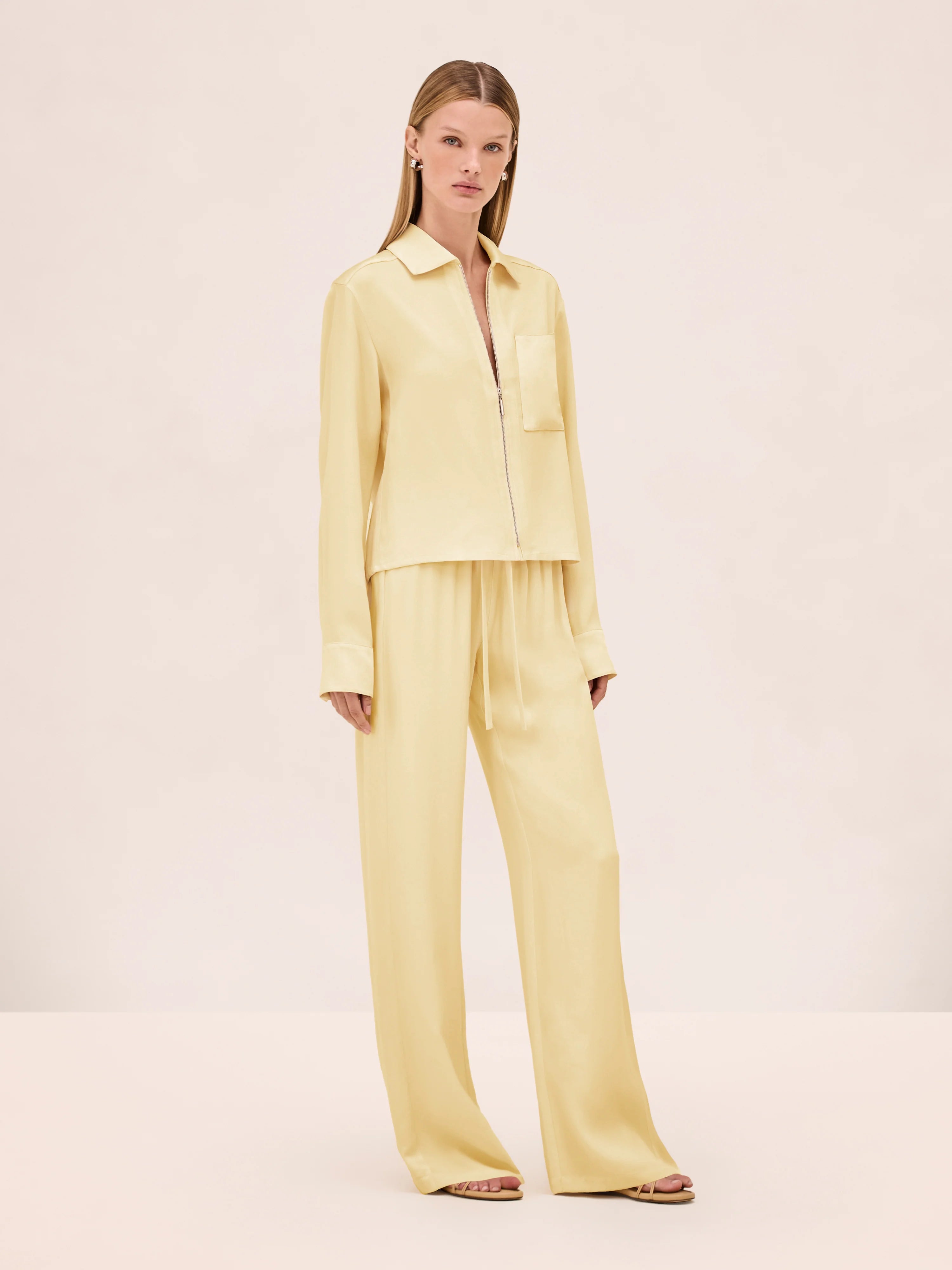 A model wears a pale yellow zip-up shirt and matching Damian Pant wide-leg trousers with an elastic drawstring waist for a polished style.