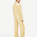 A person viewed from behind, wearing a pale yellow collared long-sleeve shirt and matching wide-leg Damian Pant for a polished style.