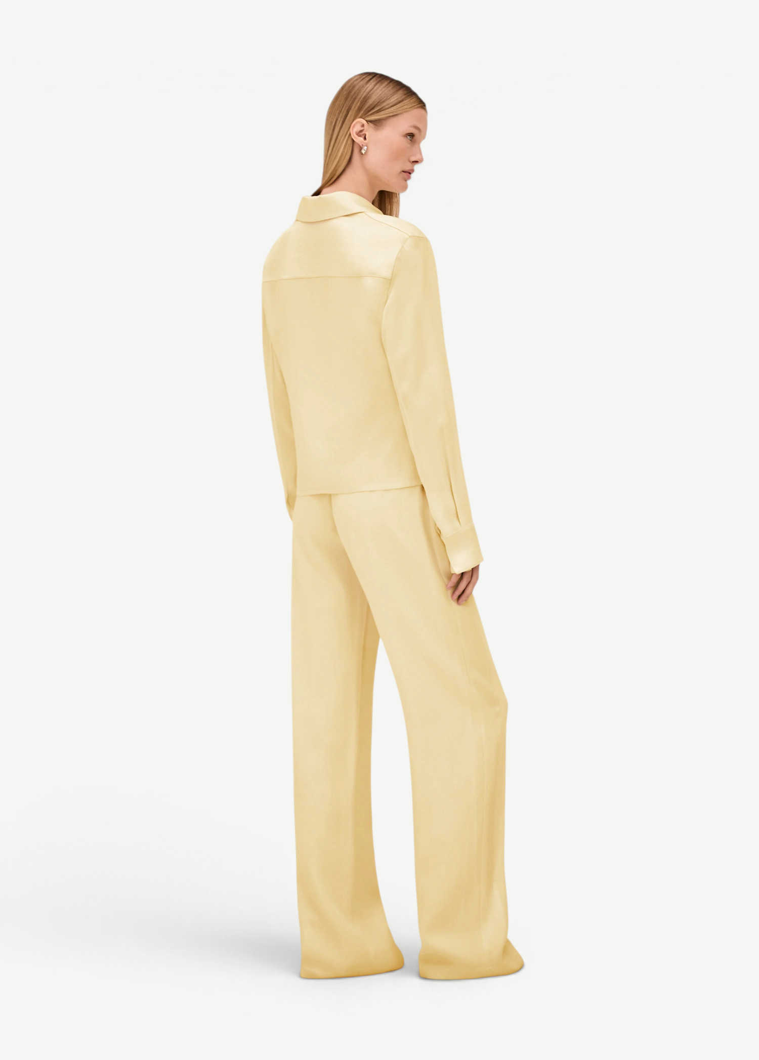 A person viewed from behind, wearing a pale yellow collared long-sleeve shirt and matching wide-leg Damian Pant for a polished style.