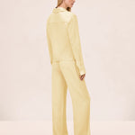 A person viewed from behind, wearing a pale yellow collared long-sleeve shirt and matching wide-leg Damian Pant for a polished style.