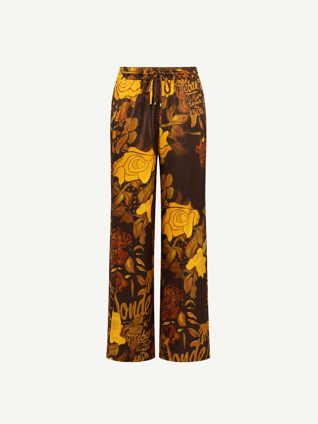 Veranera Pants: wide-leg silk twill trousers with a drawstring waist, featuring a brown and yellow floral print and overlapping script text.