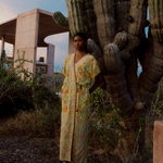 Model wearing a KABE SHOP INC long wrap dress with yellow floral sari-inspired embroidery in a desert landscape.