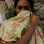 KABE SHOP INC long wrap dress in green floral sari fabric with bohemian embroidery, worn by a model near cacti.