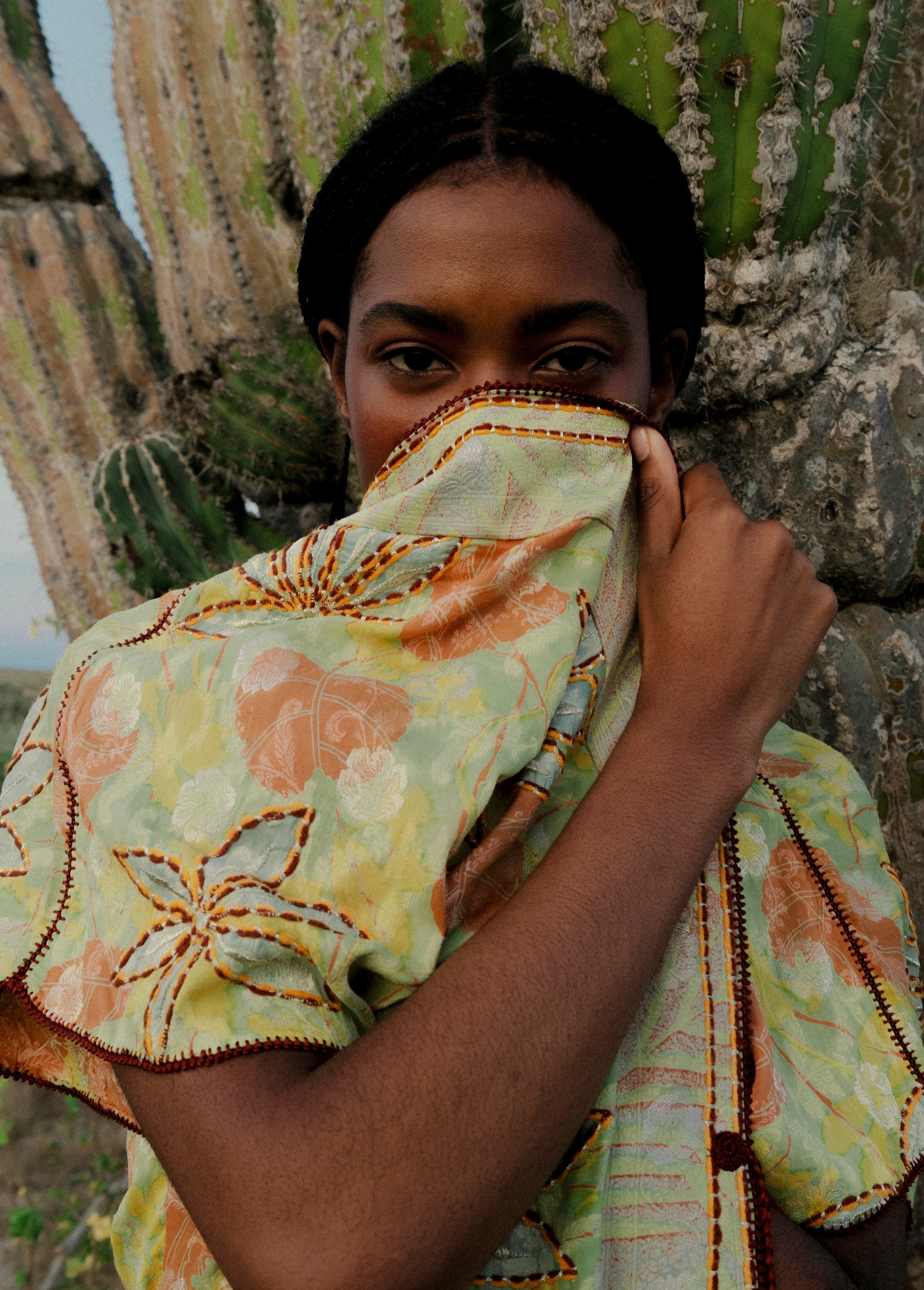 KABE SHOP INC long wrap dress in green floral sari fabric with bohemian embroidery, worn by a model near cacti.