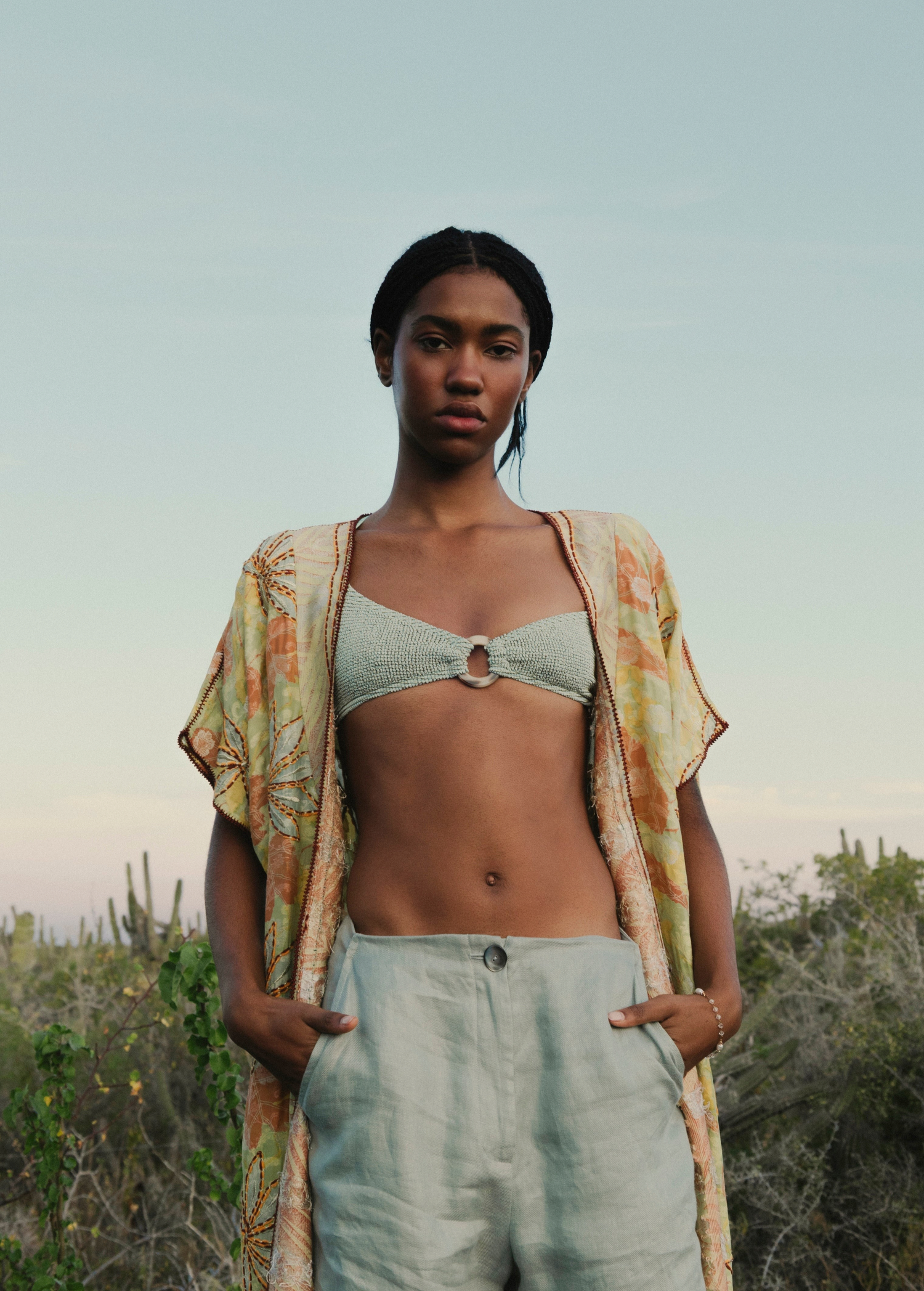 Model wearing a KABE SHOP INC bohemian long wrap robe with floral embroidery over a light green bikini top and pants