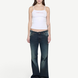 Model wearing a white KABE SHOP INC ribbed cami top with thin straps and pink logo detail, paired with flared jeans.