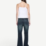 Back view of a woman wearing a KABE SHOP INC white ribbed cami top paired with dark wash flared denim jeans