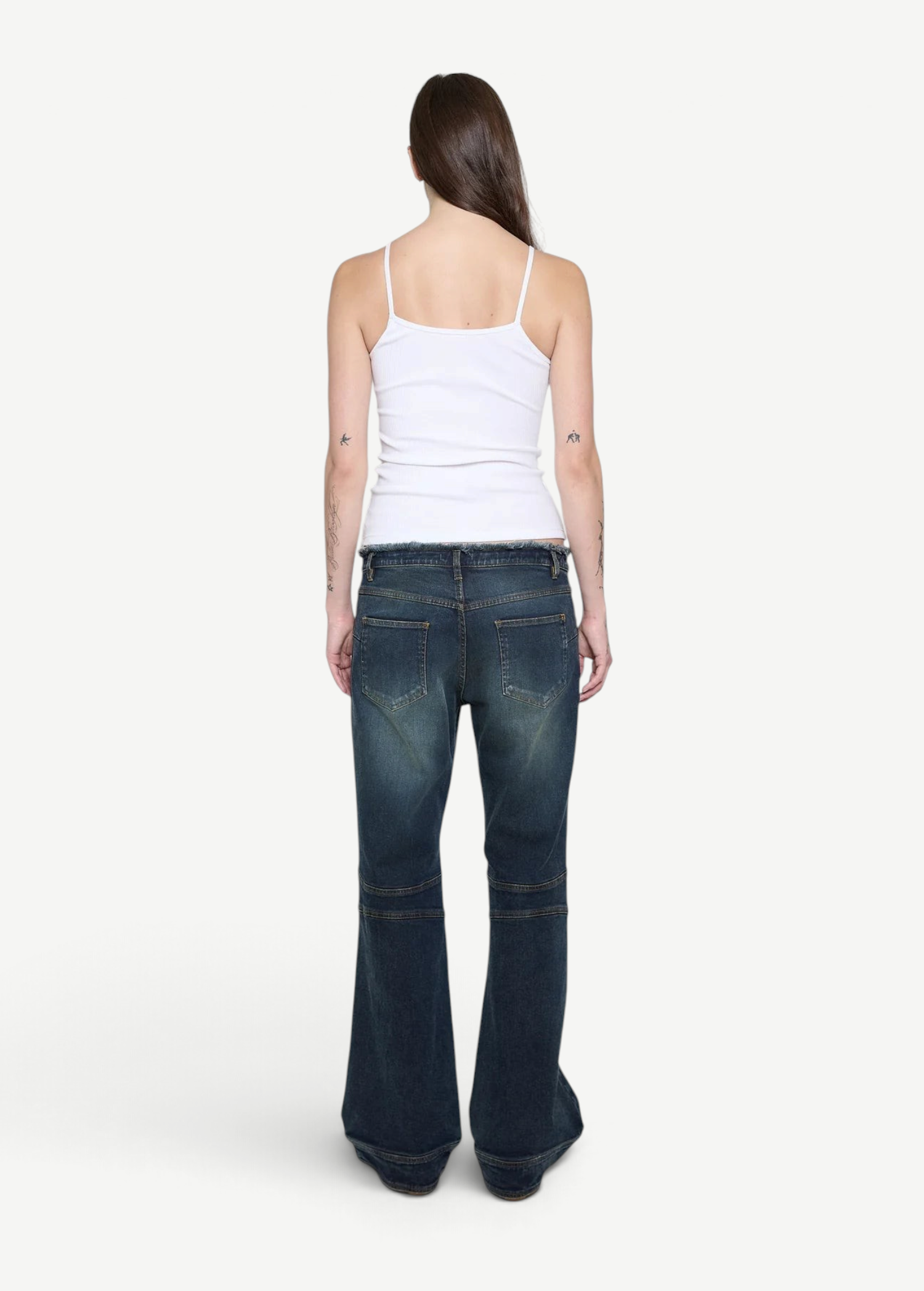 Back view of a woman wearing a KABE SHOP INC white ribbed cami top paired with dark wash flared denim jeans