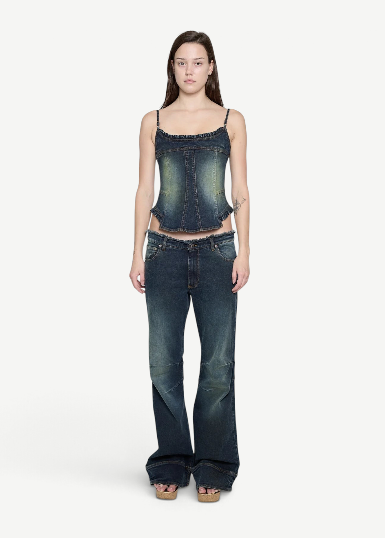 A woman wears a Denim Corset Top with ruffle accents paired with wide-leg denim jeans, creating a sculptural silhouette.