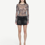 Model wearing a KABE SHOP INC black denim mini skirt with paneled detailing and a long-sleeve patterned mesh top.