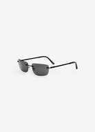 Paris rimless sunglasses feature dark rectangular lenses, thin black metal arms, and black ear tips, delivering a timeless 2000s-inspired style with reliable UV protection, as shown on a plain white background.