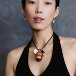 KABE SHOP INC Cowrie leather charm necklace with natural shells, stones, and pearls worn by a model in a black top.
