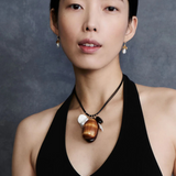 KABE SHOP INC Cowrie leather charm necklace with natural shells, stones, and pearls worn by a model in a black top.