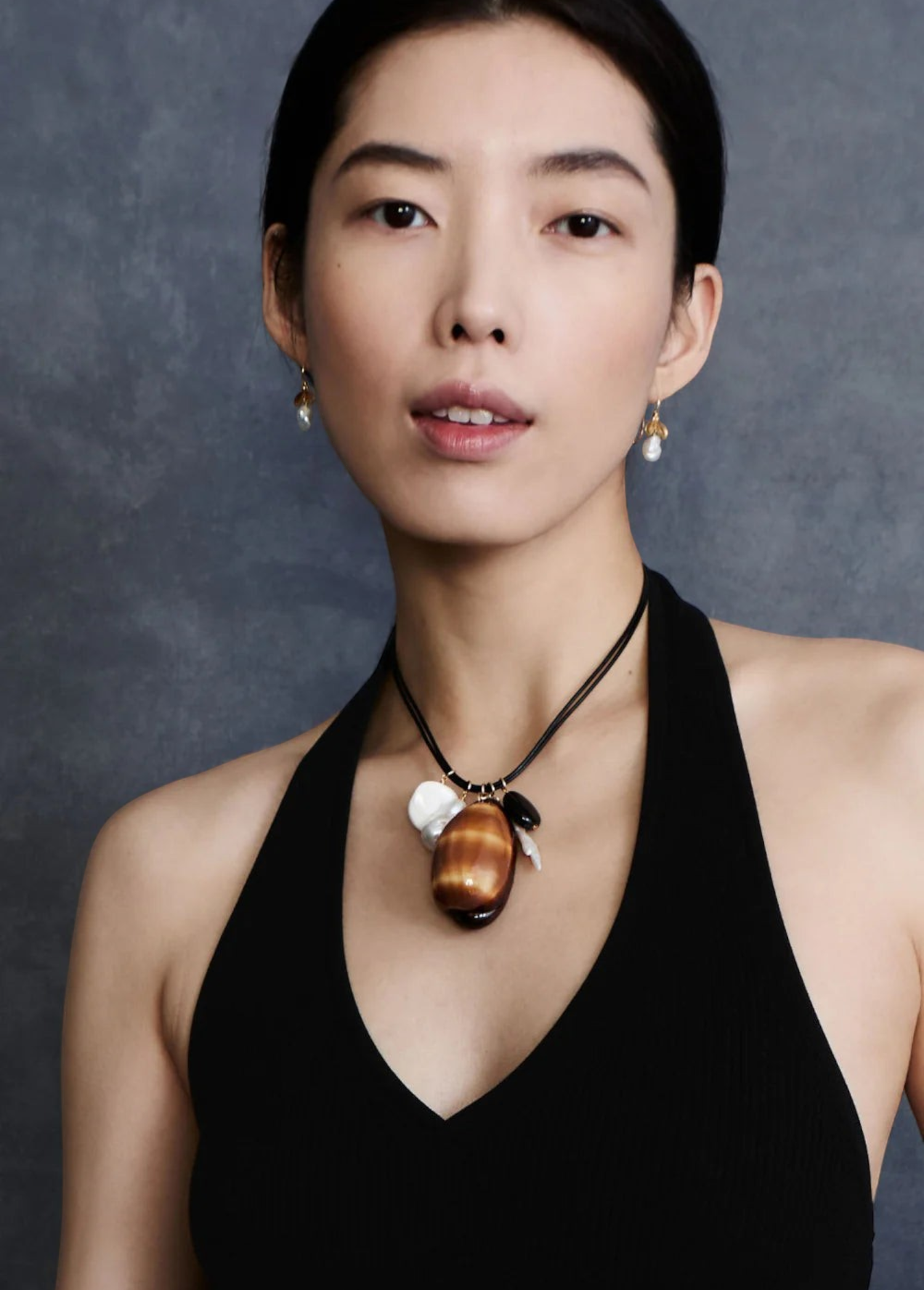 KABE SHOP INC Cowrie leather charm necklace with natural shells, stones, and pearls worn by a model in a black top.
