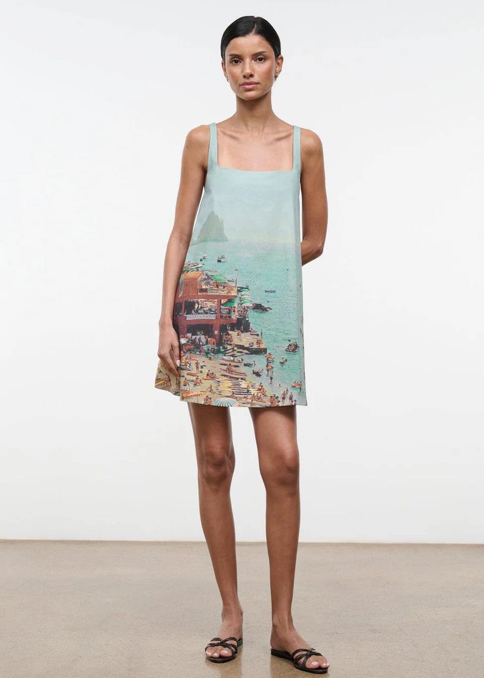 The Brio Dress features a square neckline and a printed coastal scene of a crowded beach and ocean, making it a warm-weather essential.
