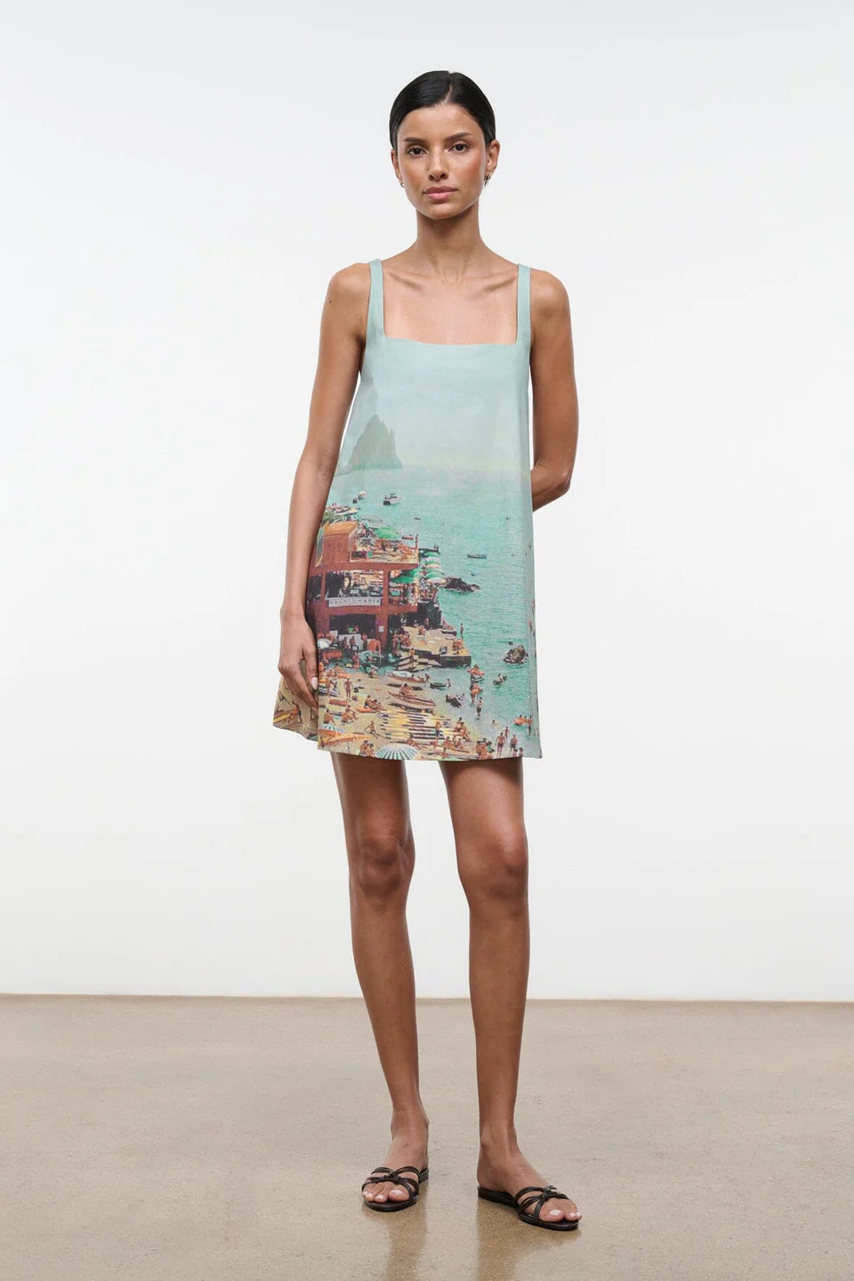 The Brio Dress features a square neckline and a printed coastal scene of a crowded beach and ocean, making it a warm-weather essential.