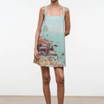 The Brio Dress features a square neckline and a printed coastal scene of a crowded beach and ocean, making it a warm-weather essential.