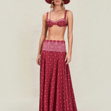A person wearing a maroon bikini top and matching Rylie Skirt featuring a white floral pattern, styled with a wide-brimmed bucket hat in the same fabric.