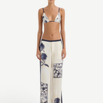 A person wearing a blue and white vintage print bikini top and matching Phillipa Trouser featuring blue side panels.