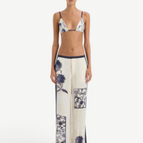 A person wearing a blue and white vintage print bikini top and matching Phillipa Trouser featuring blue side panels.