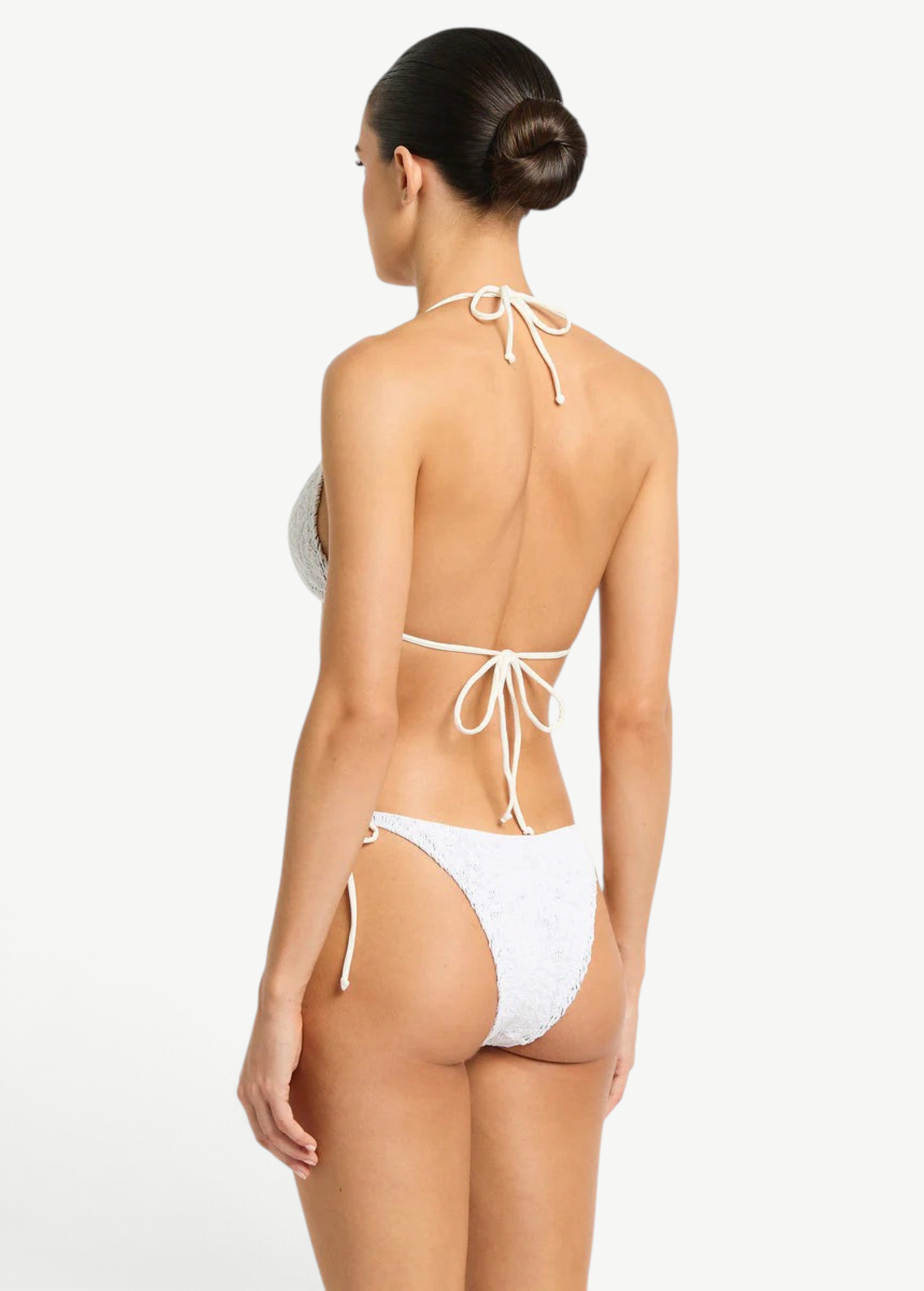 Model wearing KABE SHOP INC white lace tie-side bikini bottoms with low-rise fit and beaded side ties, back view