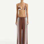Woman wearing a brown and white striped bikini with matching pants on a white background.