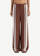 Brown wide-leg pants with white stripes worn by a person on a white background