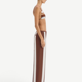 A person in profile wears a bikini top paired with matching Marais Trouser silk wide-leg trousers featuring an oversized stripe print.