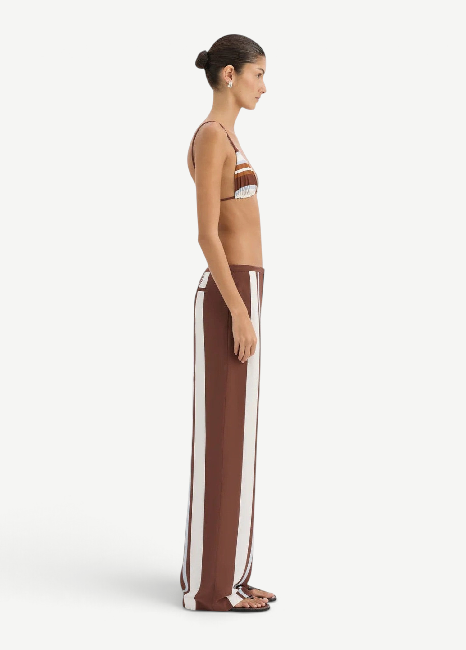 A person in profile wears a bikini top paired with matching Marais Trouser silk wide-leg trousers featuring an oversized stripe print.