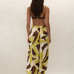 A person viewed from behind wearing a brown bikini top and Kortez Balloon Pants, which feature a relaxed, high-waisted fit and a green, white, and brown geometric pattern.