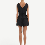 Back view of a person wearing a Klara Mini Short set, consisting of a black sleeveless v-neck top with a tie waistband and matching shorts with a scalloped hem.