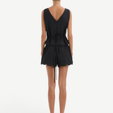 Back view of a person wearing a Klara Mini Short set, consisting of a black sleeveless v-neck top with a tie waistband and matching shorts with a scalloped hem.