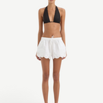 A person wearing a black bikini top and white Klara Mini Short drawstring shorts with a scalloped hem and floral cut-out embroidery.