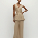 A person wearing a beige pinstripe Selan Top with a v-neck and matching wide-leg trousers, creating a relaxed silhouette with a refined tunic.