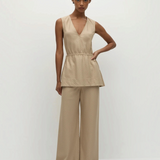 A person wearing a beige pinstripe Selan Top with a v-neck and matching wide-leg trousers, creating a relaxed silhouette with a refined tunic.