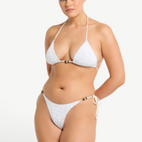 Model wearing KABE SHOP INC white textured bikini with beaded tie-side bottoms and matching triangle top