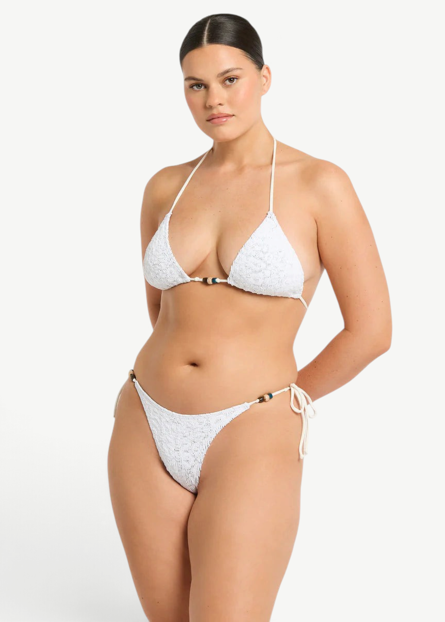 Model wearing KABE SHOP INC white textured bikini with beaded tie-side bottoms and matching triangle top