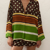 A person wearing a loose-fitting Cora Shirt and matching shorts featuring a brown and green geometric pattern with horizontal stripes.